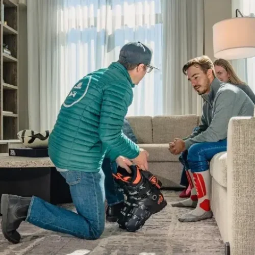 Ski Butlers technician fitting boots in a guest accommodation