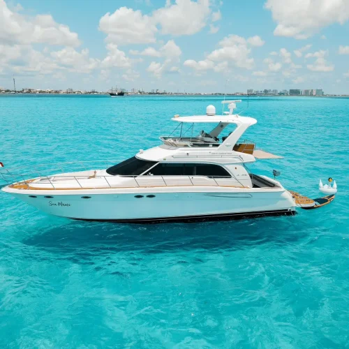 White 52ft Sea Ray yacht anchored in turquoise Cancún waters near the coastline.