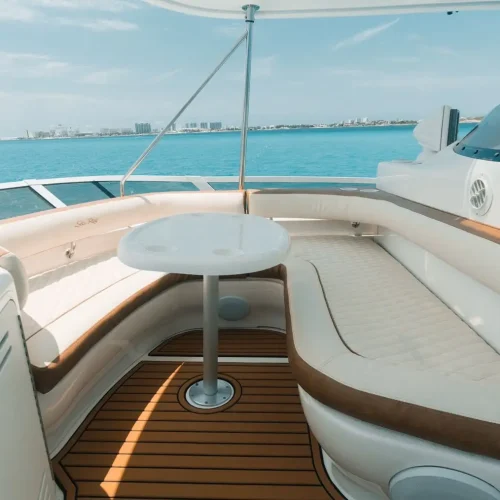 Cozy yacht seating area with cushioned benches, table, and teak deck flooring.