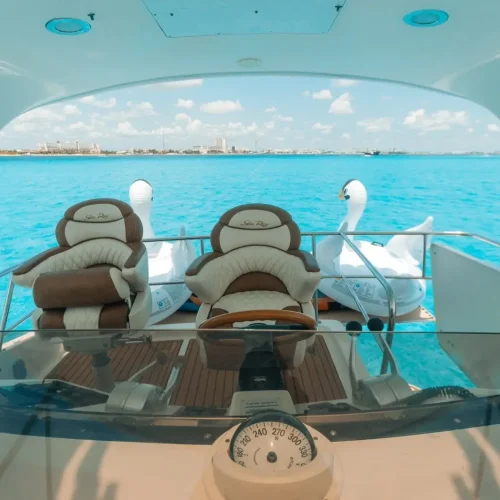 Flybridge helm with captain seats, swan floats, and ocean view behind.