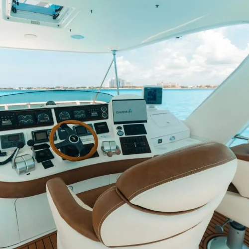 Detailed yacht flybridge helm with wooden wheel, Garmin electronics, and leather seats.