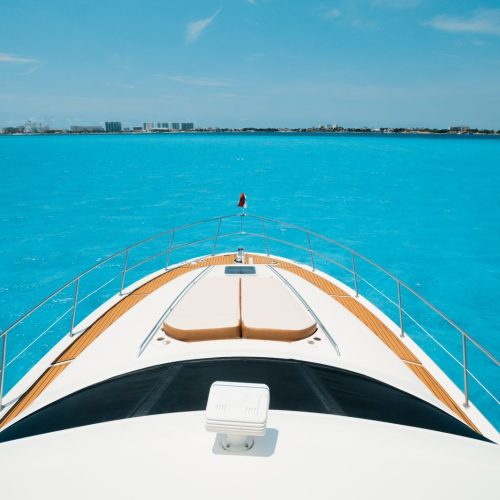 Bow view over turquoise Cancún water toward the coastline horizon.