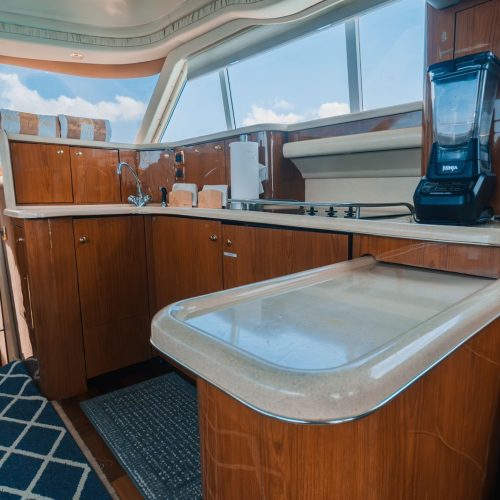 Yacht galley kitchen with wood cabinets, sink, stovetop, and blender.