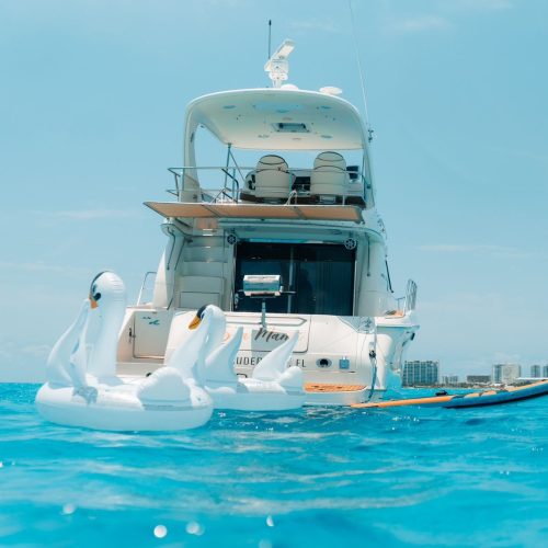 Rear view of luxury yacht with swan floats in turquoise Cancún waters.