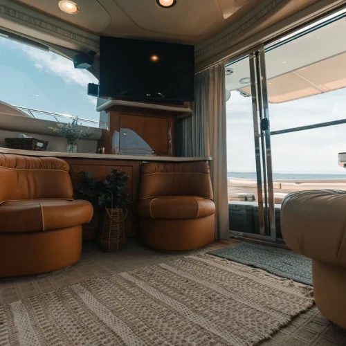 Yacht lounge with swivel leather chairs, TV, and sliding doors to sea.