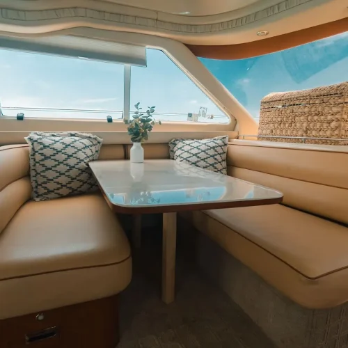 Yacht dining nook with leather booth, table, and bright ocean-view windows.