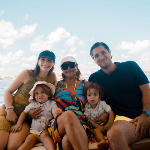 Smiling family with two young children relaxing on yacht deck in Cancún.