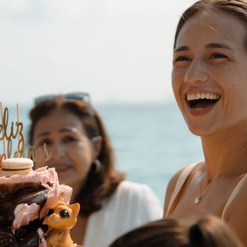 Woman laughing beside a birthday cake during a yacht celebration at sea.