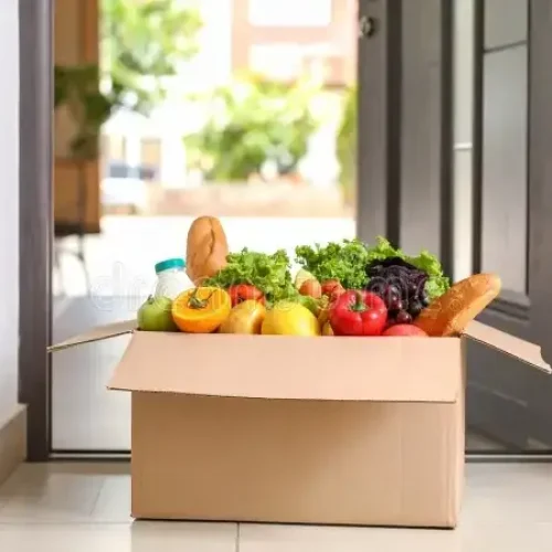 grocery-delivery-box-filled-fresh-produce-bread-near-front-door-437207292