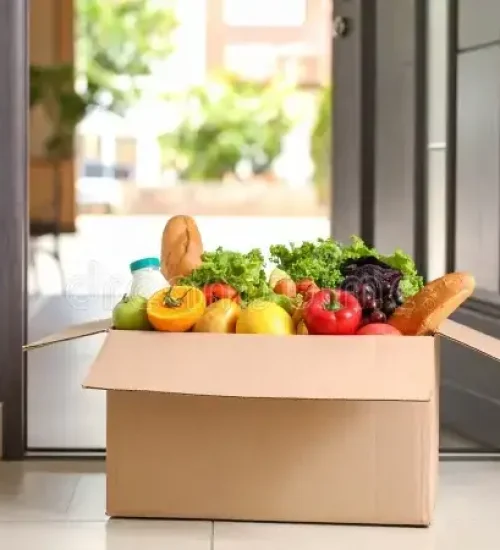 grocery-delivery-box-filled-fresh-produce-bread-near-front-door-437207292